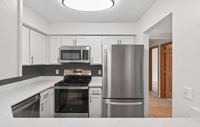 A modern kitchen with stainless steel appliances and white cabinets.