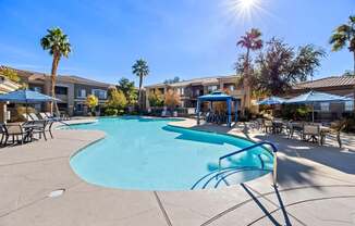 A sunny day at the pool with palm trees and apartment buildings in the background.
