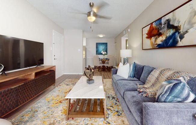 A living room with a grey couch, a wooden coffee table, and a painting on the wall.