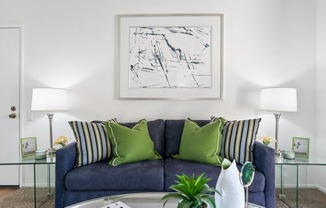 a living room with a blue couch and green pillows