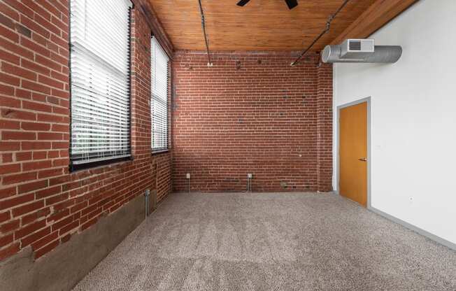 an empty room with a brick wall and a window