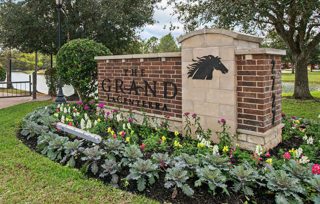 a brick sign with a black horse on it next to a flower garden