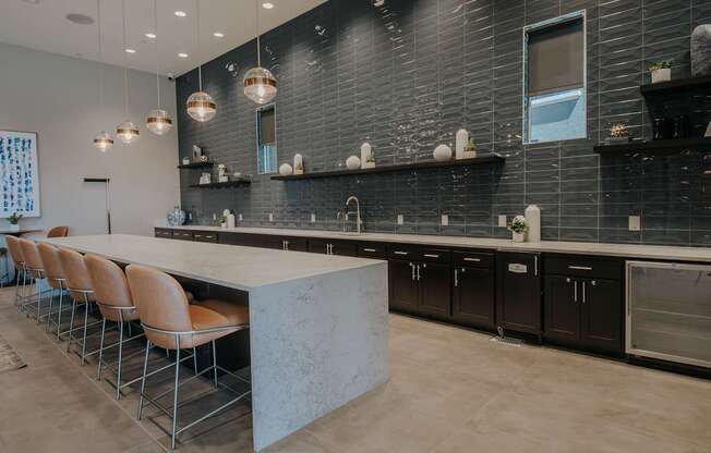 Level 25 at the Curve's modern clubhouse's kitchen with a long island and chairs.