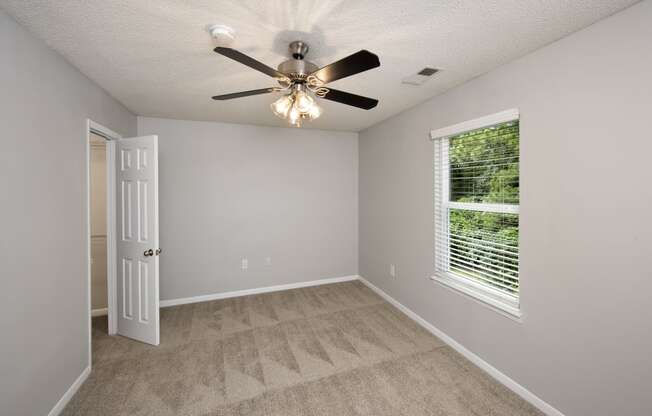 an empty bedroom with a ceiling fan and a window