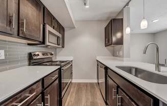 A kitchen with dark wood cabinets and a white countertop.