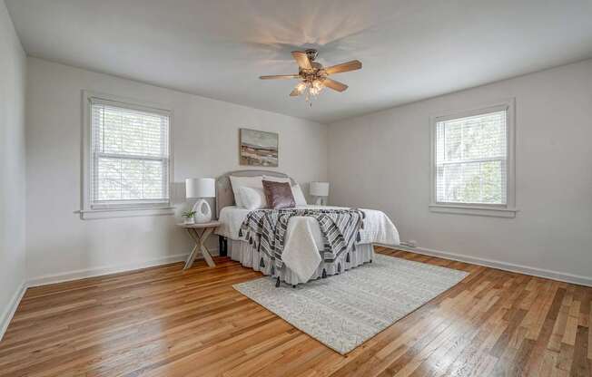 A bedroom with a bed, a fan, and a rug.