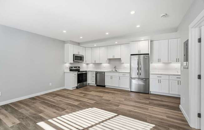 A kitchen with white cabinets and a wooden floor.