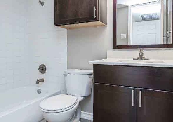 A white toilet sits in a bathroom next to a bathtub.