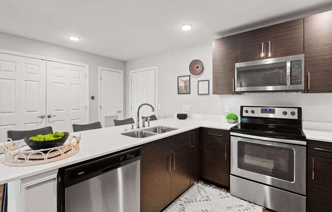 A modern kitchen with dark wood cabinets and stainless steel appliances.