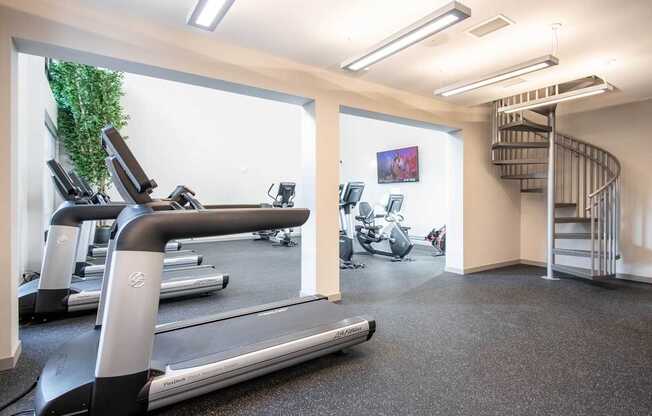 A gym with treadmills and a staircase.