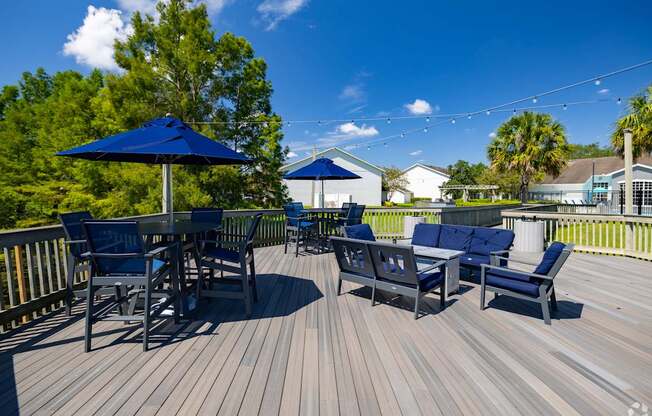 A wooden deck with blue chairs and umbrellas.