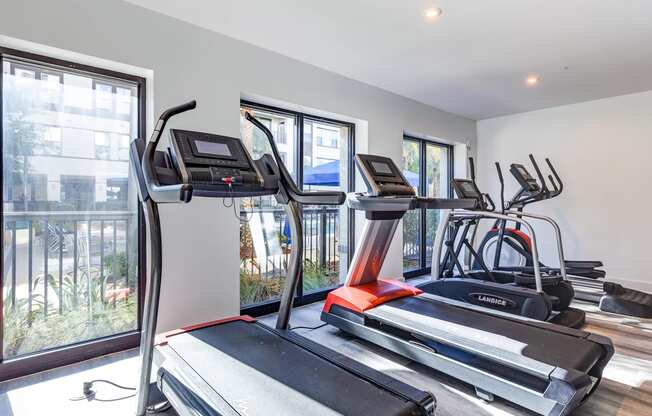 two treadmills and other exercise equipment in an apartment gym