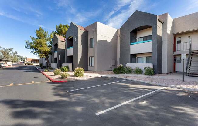 A parking lot in front of a modern building with a clear blue sky.