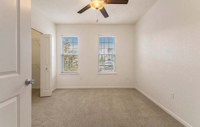 A bedroom with a ceiling fan and two windows at Lynbrook Apartments and Townhomes, Elkhorn, NE, 68022