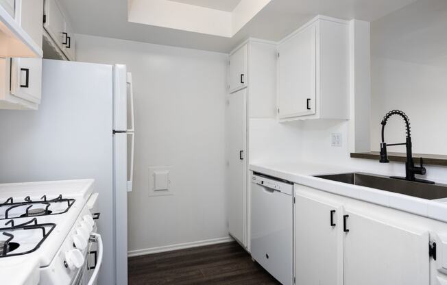 an empty kitchen with white cabinets and a white stove and refrigerator