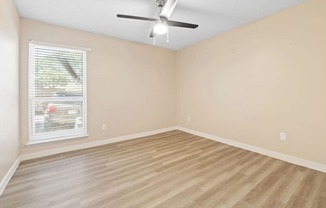 an empty living room with a ceiling fan and a window