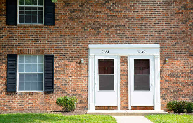 A red brick building with a white door and window.