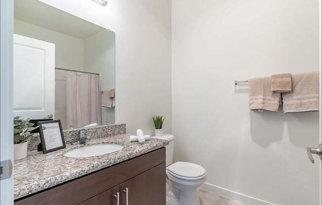 A bathroom with a toilet, sink, and mirror at Riverplace Apartment Homes, Independence, OR