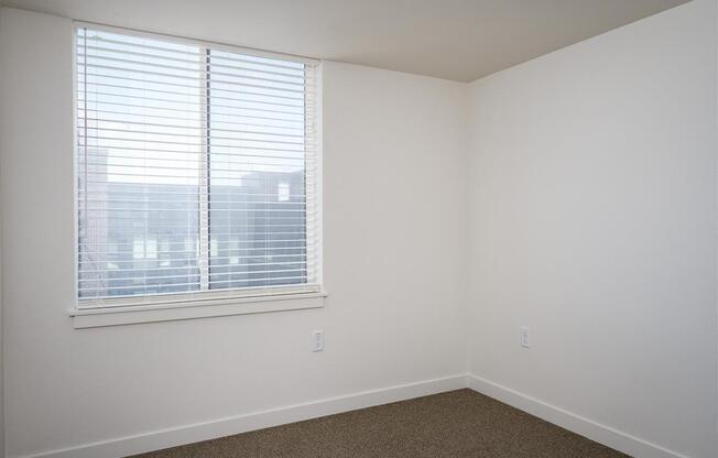 an empty room with a large window and white walls