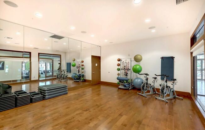 View of Yoga Space, Showing Stationary Bicycles, Exercise Balls, Medicine Balls, and Yoga Mats at The Marq Highland Park Apartments