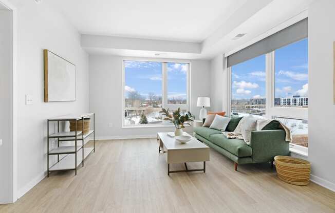 a living room with a green couch and large windows