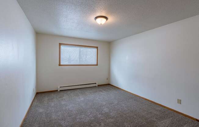 a bedroom with white walls and a window. Fargo, ND Schrock Apartments