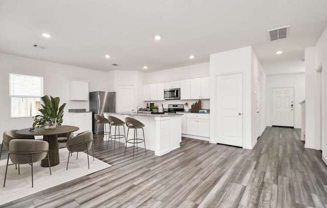 A modern kitchen with white cabinets and a wooden floor.