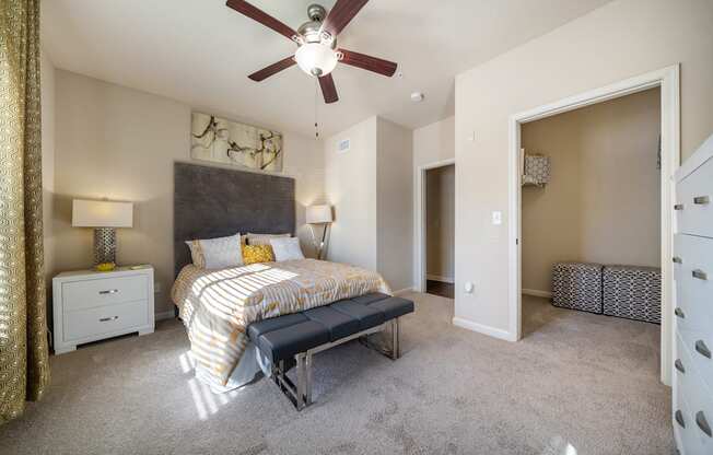 A bedroom with a bed, nightstand, and a ceiling fan.