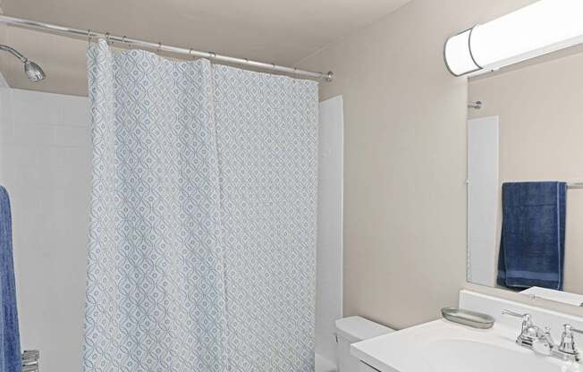 A white sink with a blue towel hanging on the mirror.
