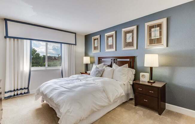 A bedroom with a large bed and a window with curtains.
