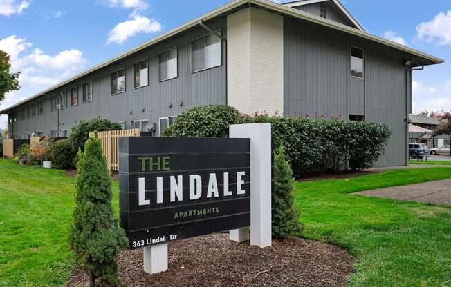 A sign for The Lindale Apartments stands in front of a grey building.