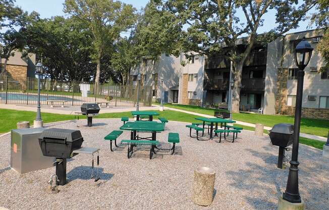 a park with picnic tables and grills in front of a building