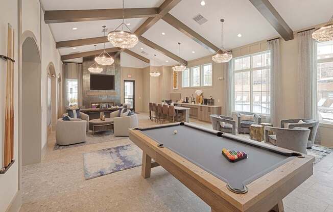 A pool table is in the middle of a room with a bar and a couch.