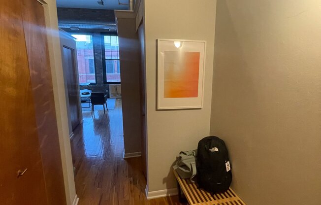 a hallway with a bench and a backpack on the floor