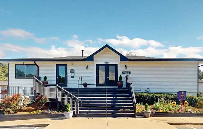 A white house with a black roof and a black staircase leading to the front door.