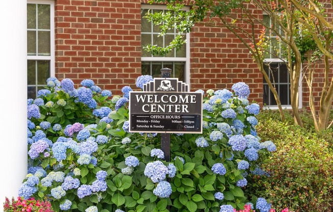 welcome center sign surrounded by blue hydrangea in front of Fenwyck Manor Clubhouse
