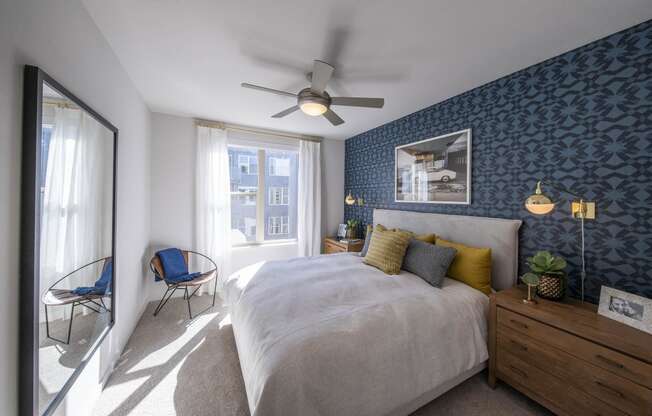 a bedroom with blue wallpaper and a white bed