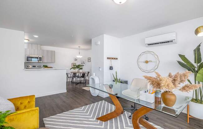 a living room with a glass table and a kitchen