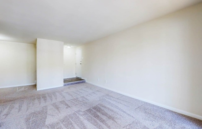 an empty living room with white walls and carpet