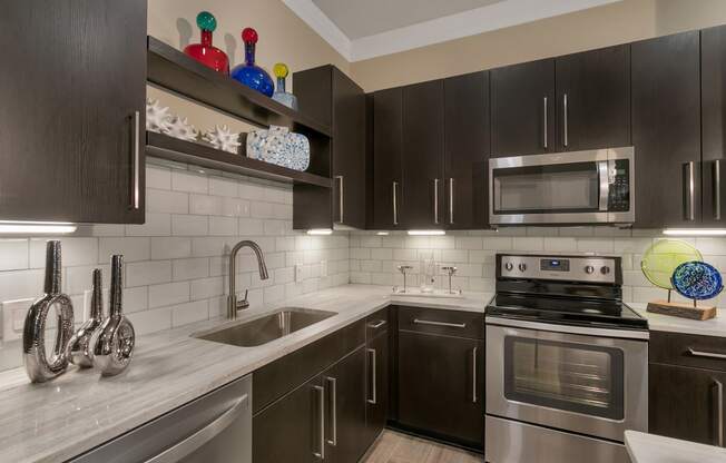 a kitchen with stainless steel appliances and black cabinets at Aster Apartments, Beachwood