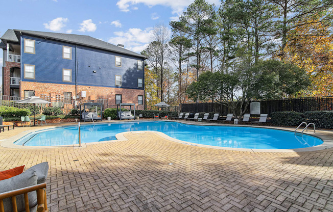 A swimming pool surrounded by a brick patio and a brick building in the background.