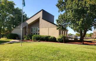 Willow Creek Apartments - Exterior view of the clubhouse with lush landscaping.