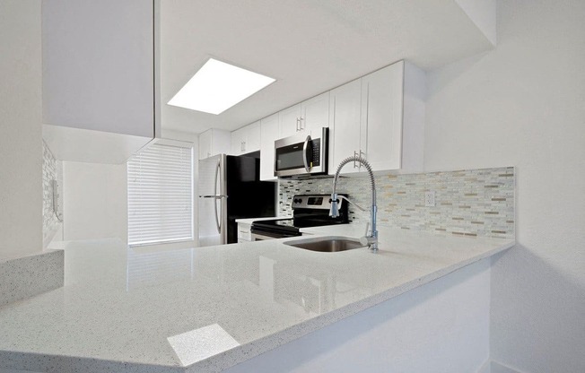 a white kitchen with a sink and a microwave