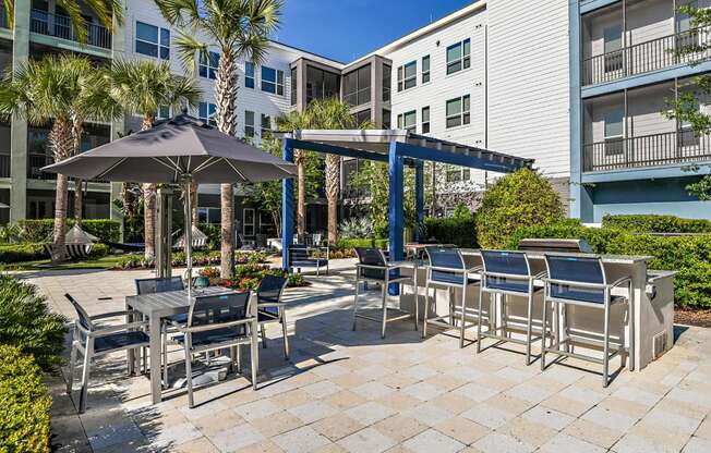 a patio with tables and chairs and umbrellas at an apartment building