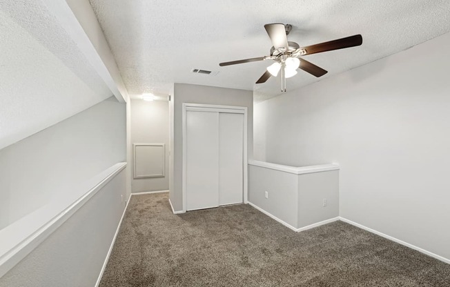 A room with a ceiling fan and carpeted floor.