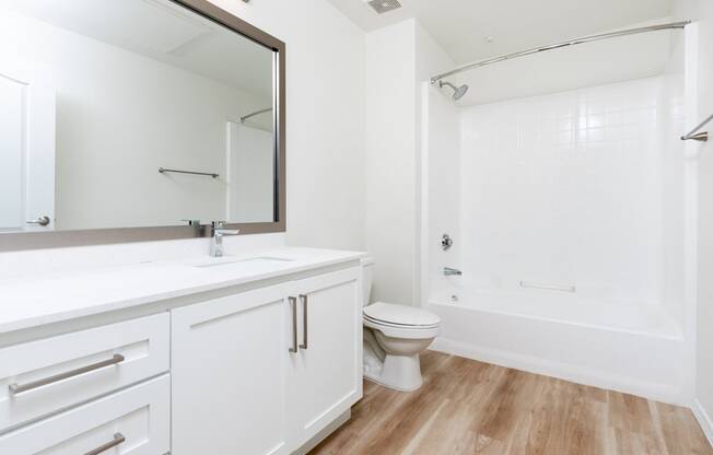 a bathroom with white cabinets and a white toilet and a shower