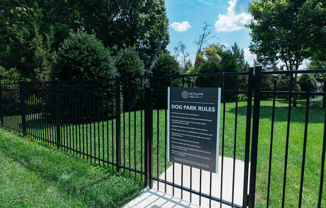 A sign in front of a fence that says Dog Park Rules.