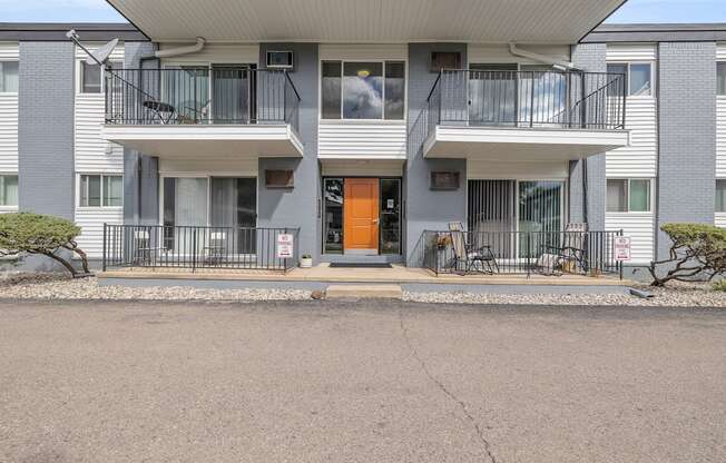 A modern apartment building with a grey facade and a central orange door.
