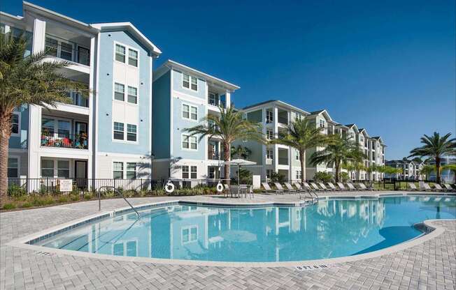 A swimming pool in front of a row of apartment buildings.