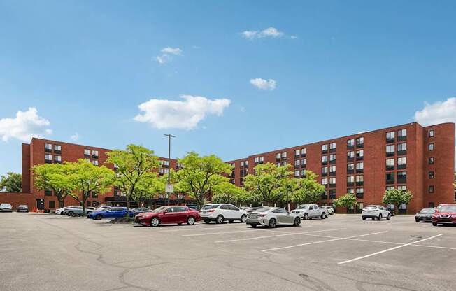 A parking lot with cars and a red building in the background.